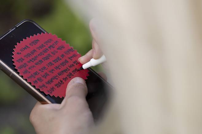 집회 시작 전 연대차 방문한 참석자가 카네이션 메모지에 지혜복 선생님에게 보내는 글을 적고 있다. ⓒ시사IN 이명익