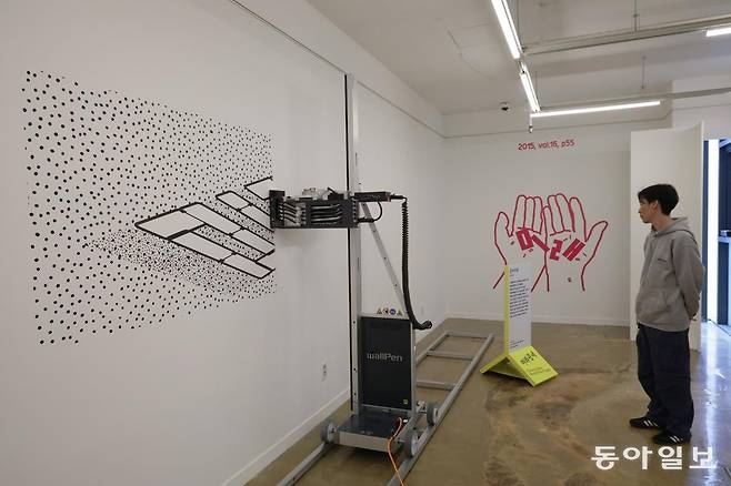 15일 서울 종로구 KCDF 갤러리에서 ‘2025 공예주간’의 한 관계자가 개막 전시품을 미리 살펴보고 있다. 레이저 프린팅 로봇이 ‘미래’라는 글씨를 벽에 새기는 ‘공예미래’라는 작품이다. 
박형기 기자 oneshot@donga.com