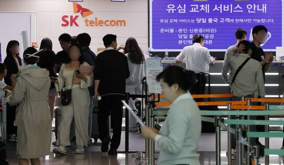 SK Telecom users wait in line to switch their SIM cards at a booth in Incheon International Airport on May 8. [NEWS1]