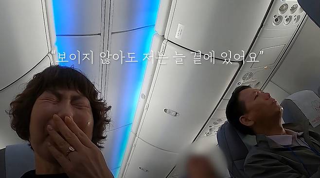 순직 소방공무원의 유가족들이 치유 여행을 떠나는 기내에서 어머니(왼쪽)가 인공지능(AI)으로 재생된 아들의 목소리를 듣고 눈물을 흘리고 있다.  소방청