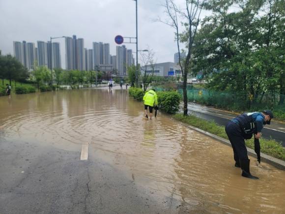경기 양주시 옥정 호수공원 근처 도로가 갑자기 내린 비로 침수되자, 경찰이 차량통행을 금지하고 배수 작업을 하고 있다. [경기북부경찰청 제공]