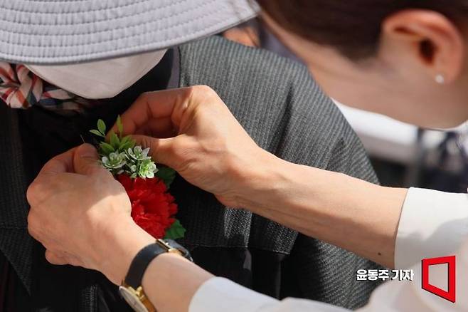 지난 8일 어버이날을 맞아 서울 동대문구 밥퍼나눔운동본부에서 자원봉사자들이 어르신들에게 카네이션을 달아드리고 있다. 윤동주 기자