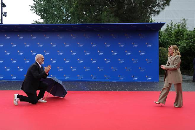 멜로니 총리를 무릎 꿇고 환영하는 라마 총리. /AP 연합뉴스