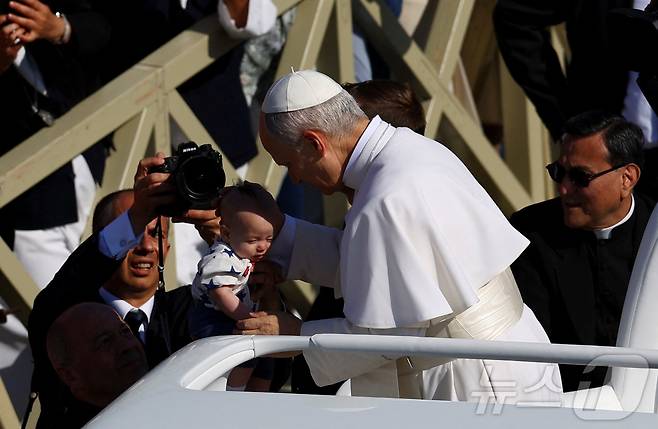 교황 레오 14세가 즉위 미사를 위해 포프모빌(교황 전용차량)을 타고 바티칸 성베드로 광장에서 도착하면서 한 아기를 축복하고 있다. 2025.5.18 ⓒ 로이터=뉴스1 ⓒ News1 신기림 기자