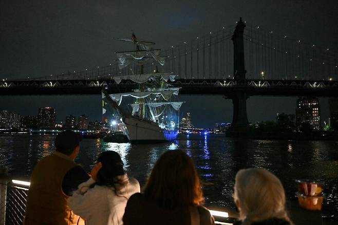 17일 뉴욕 맨해튼 다리 위에 올라간 시민들이 브루클린 다리에 부딪친 멕시코 해군 범선을 바라보고 있다. 이번 충돌 사고로 범선은 돛대 세 개가 모두 부러졌으며, 최소 22명의 사상자가 발생했다. 뉴욕/AFP연합뉴스