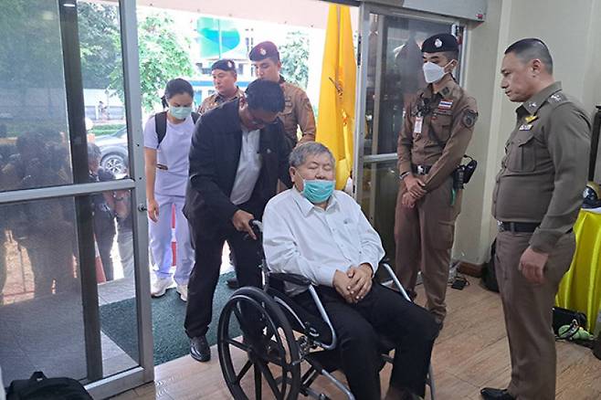 ‘이탈리안-타이 개발(ITD)’의 쁘렘차이 회장이 16일 아침 휠체어를 타고 경찰서에 들어서고 있다.(사진출처 : 방콕포스트)