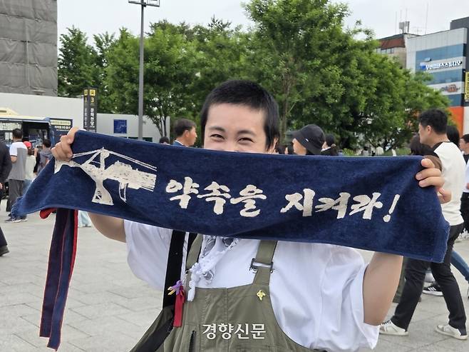 지난 17일 광주 동구 금남로에서 열린 5.18 전야제에 참여한 한 시민이 슬로건을 들고 웃고 있다. 우혜림 기자