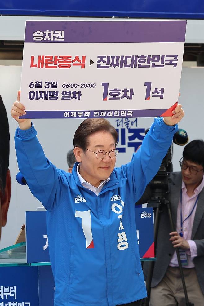 이재명 더불어민주당 대통령 후보가 19일 서울 용산구 용산역 광장에서 열린 집중유세에서 장경태 의원으로부터 이재명 열차 승차권을 받아 높이 들어올리고 있다. 사진=뉴스1