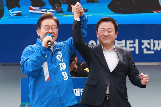 이재명 더불어민주당 대선 후보가 지난 17일 오후 광주 서구 김대중컨벤션센터 광장에서 열린 선거 유세에서 이 후보 지지를 선언한 김용남 전 새누리당(현 국민의힘) 의원의 손을 잡고 있다. 김성룡 기자