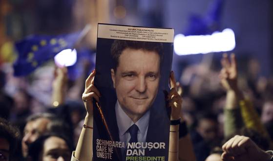 19일(현지시간) 루마니아 부쿠레슈티에서 첫 번째 출구조사 결과가 발표된 후 한 지지자가 니쿠쇼르 단 부쿠레슈티 시장의 승리를 축하하며 후보 포스터를 들고 있다. EPA=연합뉴스