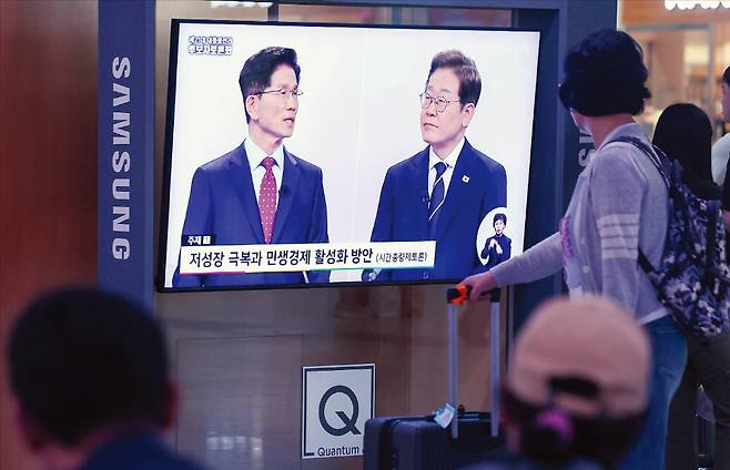 서울역에서 시민들이 ﻿18일 열린 대선 후보 TV 토론회에서 김문수 국민의힘 후보(왼쪽)와 이재명 더불어민주당 후보가 발언하는 모습을 보고 있다.  연합뉴스