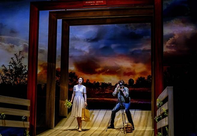 뮤지컬 ‘매디슨 카운티의 다리’에서 프란체스카(조정은·왼쪽)가 노래부르고, 로버트(최재림)는 사진을 찍고 있다. <쇼노트>