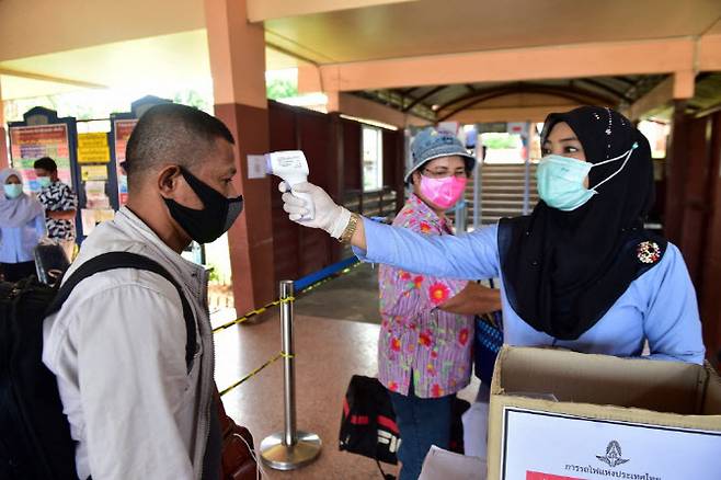지난 2020년 코로나19 팬데믹 당시 태국 남부 나라티왓주의 한 기차역에서 역무원이 승객의 체온을 측정하고 있다.(사진=AFP)