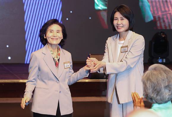 국민의힘 김문수 대선 후보의 부인 설난영 씨와 더불어민주당 이재명 대선 후보의 부인 김혜경 씨가 12일 서울 중구 신라호텔에서 열린 중앙신도회 창립 70주년 기념식에서 손을 맞잡고 있다. 2025.5.12 [사진=연합뉴스]