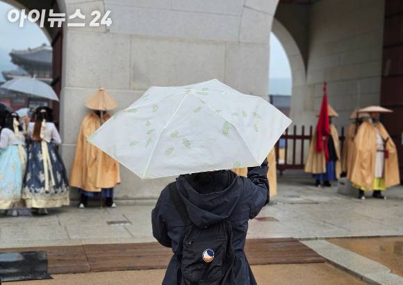 비가 내리는 가운데 우산을 든 관광객이 경복궁 수문장 교대식을 보고 있다. [사진=아이뉴스24 DB]