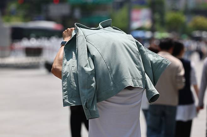 서울 한낮 기온이 26도까지 오르며 더운 날씨를 보인 14일 서울 종로구 광화문에서 한 시민이 겉옷으로 햇빛을 가리고 있다. [사진 = 연합뉴스]