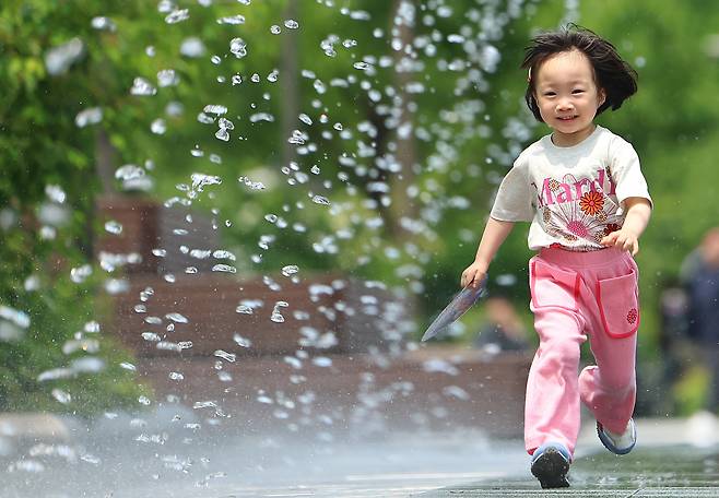 전국 대부분 낮 기온이 25도 이상을 기록하는 등 초여름 날씨를 보인 20일 서울 광화문광장을 찾은 어린이가 환하게 웃으며 분수터널을 지나고 있다. [연합]