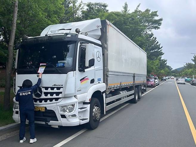 [창원=뉴시스] 강경국 기자 = 경남 창원시 진해구 경제교통과 직원들이 주차선 침범으로 주행차로 안전을 위협하는 차량에 대해 계도장을 부착하고 있다. (사진=창원시청 제공). 2025.05.20. photo@newsis.com *재판매 및 DB 금지