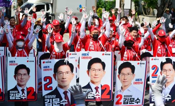 국민의힘 충북도당 선거대책위원회가 지난 13일 충북 청주시 성안길에서 열린 출정식에서 국민의힘의 기호인 ‘2’가 적힌 장갑을 양손에 낀 채 두 팔을 번쩍 치켜들고 있는 모습. 청주 뉴시스