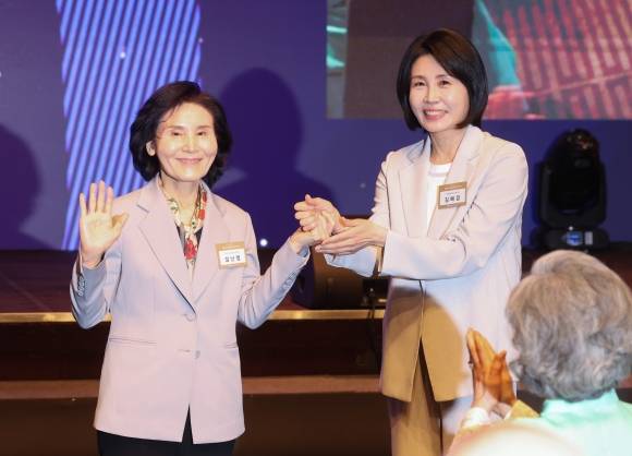 국민의힘 김문수 대선 후보의 부인 설난영 씨와 더불어민주당 이재명 대선 후보의 부인 김혜경 씨가 12일 서울 중구 신라호텔에서 열린 중앙신도회 창립 70주년 기념식에서 손을 맞잡고 있다. 2025.5.12 연합뉴스