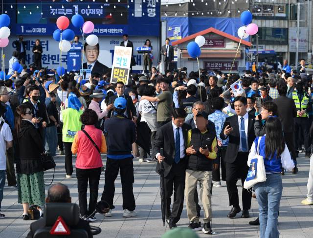 이재명 더불어민주당 대선 후보가 14일 경남 통영 강구안 문화마당에서 유권자들에게 지지를 호소하고 있는 가운데 이 후보에게 항의하던 한 시민이 경호원들에 의해 제지당하고 있다. 통영=오승현 기자 2025.05.14