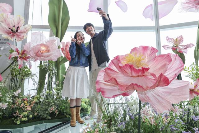 서울스카이 모델들이 20일 서울 송파구 롯데월드타워 전망대 서울스카이 118층 스카이데크에 핑크빛 대형 꽃들로 꾸며진 '유니버스 플라워' 앞에서 '블루밍 유니버스' 기획을 알리고 있다. 오승현 기자 2025.05.20