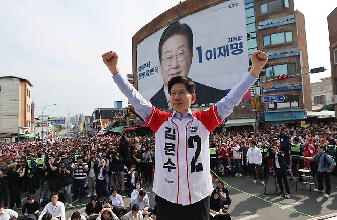김문수 국민의힘 대선후보가 14일 오후 경남 밀양시 중앙로에서 유세를 하고 있다. 김문수 후보 뒤로 이재명 후보의 대형 현수막이 보인다. / 김지호 기자