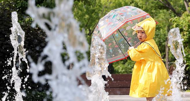 전국 대부분 지역 낮 기온이 25도 이상으로 올라 초여름 날씨를 보인 지난 20일 서울 종로구 광화문광장 바닥분수에서 우의를 입은 한 어린이가 물놀이를 하며 더위를 식히고 있다. /뉴스1