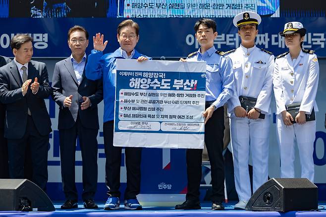 이재명(왼쪽 세번째) 더불어민주당 대통령 후보가 부산·경남(PK) 지역 유세에 나선 14일 부산 부산진구 서면에서 권기흥 에이치라인해운해상직원노조 위원장과 해양수도 부산 협약서에 서명한 뒤 기념 촬영하고 있다./뉴스1