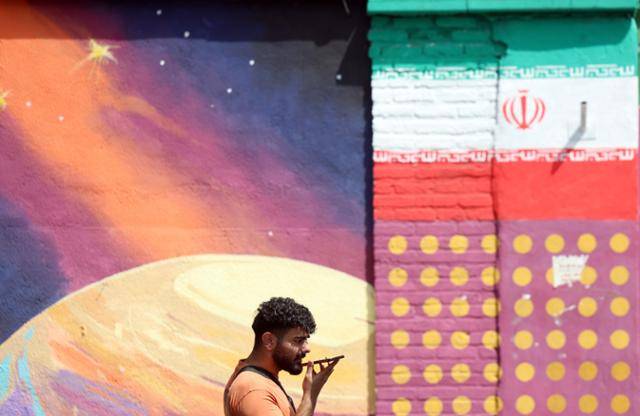 한 이란 남성이 지난 5일 이란 테헤란에서 이란 국기가 그려진 벽화 앞을 지나가고 있다. 테헤란=EPA 연합뉴스