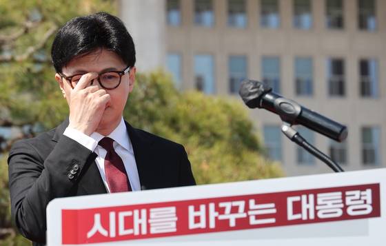 Former conservative People Power Party (PPP) leader Han Dong-hoon, props up his glasses while announcing his bid for the presidential race in front of the National Assembly in Yeouido, western Seoul, on April 10. [YONHAP]
