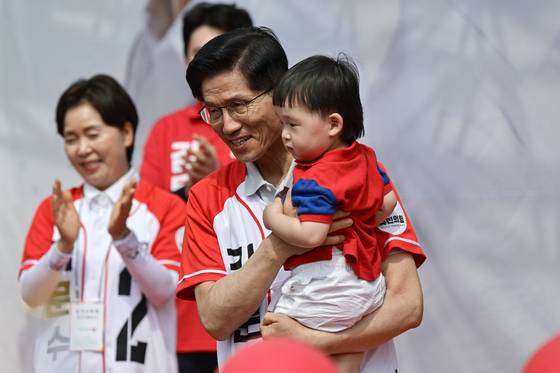 People Power Party candidate Kim Moon-soo carries a child during his campaign in Gimpo, Gyeonggi on May 21. [LIM HYUN-DONG]