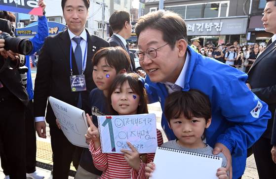 Democratic Party presidential candidate Lee Jae-myung pose for a photograph with children during his campaign in South Gyeongsang on May 14. [KIM SEONG-RYONG]