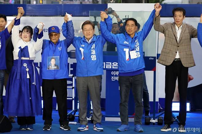 [김포=뉴시스] 조성우 기자 = 이재명(가운데) 더불어민주당 대선후보가 20일 경기 김포시 구래역 문화의 거리에서 열린 유세에서 김유택(오른쪽) 전 농구감독 등 시민인사들과 손을 잡고 기념촬영하고 있다. 2025.05.20. xconfind@newsis.com /사진=조성우