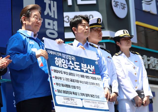 더불어민주당 이재명 대선 후보가 14일 부산 부산진구 서면 젊음의 거리에서 열린 유세에서 권기흥 에이치라인해운해상직원노조 위원장과 해양수도 부산 협약서에 서명한 후 기념 촬영하고 있다. 연합뉴스