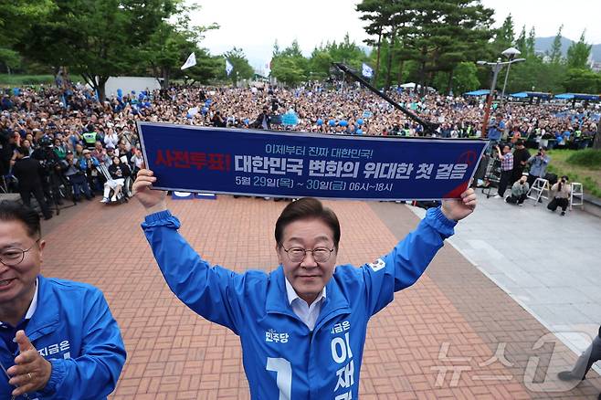 이재명 더불어민주당 대통령 후보가 22일 오후 경남 양산시 양산워터파크공원에서 열린 유세에서 '사전투표! 대한민국 변화의 위대한 첫 걸음'이라고 적힌 현수막을 들어보이고 있다. (공동취재) 2025.5.22/뉴스1 ⓒ News1 이재명 기자