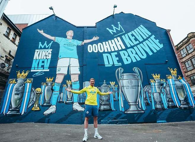 이번 시즌을 끝으로 잉글랜드 프리미어리그(EPL) 맨체스터시티(맨시티)를 떠나는 케빈 더브라위너가 지난 10년간 각종 대회에서 수집한 트로피와 함께 그려진 자신의 벽화 앞에서 벽화와 똑같은 자세를 취하며 기뻐하고 있다. 벽화에는 팬들이 그를 칭하는 ‘킹, 더브라위너’라고 적혀 있다. 사진 출처 더브라위너 인스타그램