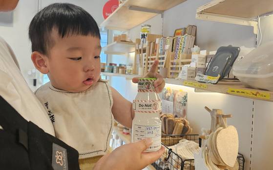 21일 오후 4시 서울 성동구 송정동 소재 제로웨이스트 상점 '베러얼스'에서 오한결(1) 군이 엄마 이슬기(35)씨의 품에서 공병에 담긴 유아용 세제를 보고 있다. 사진 정은혜 기자
