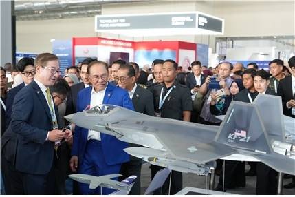 지난 20일(현지시간) 말레이시아 랑카위에서 열린 방산전시회 ‘LIMA 2025’를 찾은 안와르 이브라힘 말레이시아 총리(파란색 정장)에게 강구영 한국항공우주산업(KAI) 사장이 국내에서 개발한 KF-21의 모형 앞에서 설명하고 있다. 한국항공우주산업 제공]