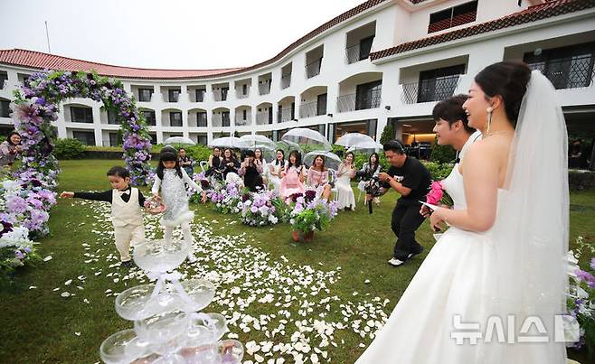 [제주=뉴시스] 우장호 기자 = 21일 오후 제주시 조천읍 에코랜드 호텔 정원에서 중국인 남여 한쌍이 야외 결혼식을 치르고 있다. 매년 5월20일과 21일은 중국의 '결혼 대목'이다. 숫자 520과 521의 중국어 발음 '우얼링'과 '우얼이'가 '사랑해'라는 중국어 '워아이니'와 비슷하게 읽혀 연인들의 기념일로 통한다. 2025.05.21. woo1223@newsis.com