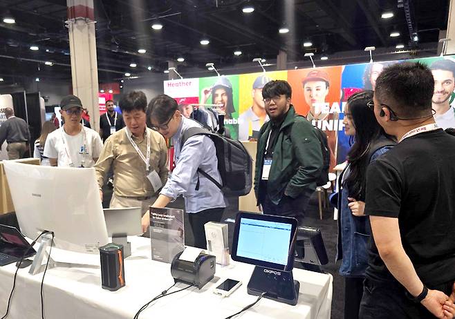 글로벌 바이어가 테이블오더를 시연중이며, 추가 시연을 위해 줄을 선 모습