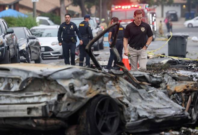 22일 미 샌디에이고 주택단지에서 발생한 소형비행기 추락사고 현장에서 조사관들이 사고 원인 등을 조사하고 있다. 샌디에이고/AFP 연합뉴스