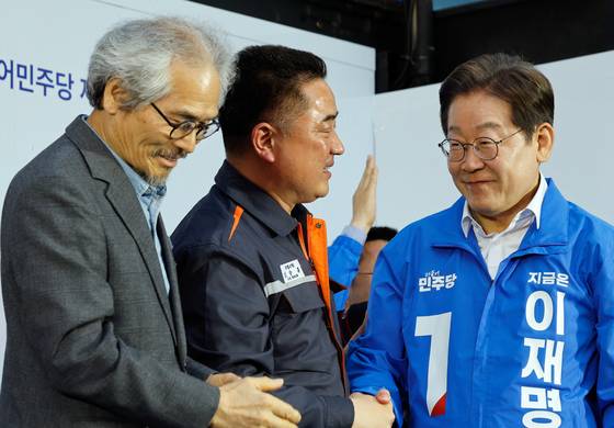 이재명 더불어민주당 대선 후보가 지난 14일 오후 경남 거제시 엠파크 차없는 거리를 찾아 유세 도중 한화오션에 근무하는 신승훈 씨(가운데, 전 금속노조 대우조선지회 수석부위원장)와 악수하고 있다. 뉴스1