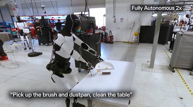 테슬라 옵티머스 로봇이 빗자루로 책상을 청소하는 모습.  X 게시물 캡처