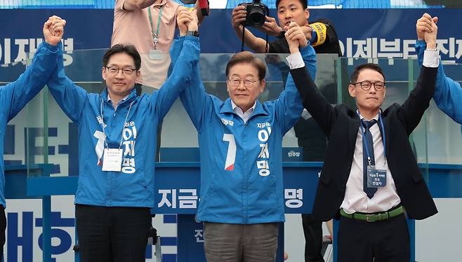 이재명 더불어민주당 대선 후보가 22일 경남 양산워터파크공원에서 열린 집중유세에서 김경수 총괄선대위원장 등과 손을 맞잡고 시민들을 향해 인사하고 있다.  [연합]