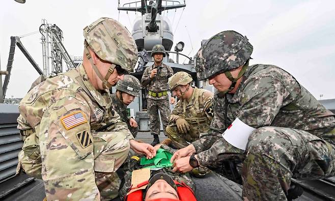 한미연합군사령부가 지난 22일 진행한 연합·합동 의무지원훈련 중 한미 장병이 고속정에서 후송을 위해 척추부상을 입은 해병대 장병을 들것에 고정시키고 있다. 한미연합군사령부 제공