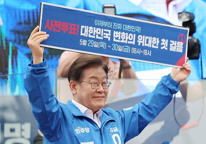 이재명 더불어민주당 대선 후보가 22일 경남 양산워터파크공원에서 열린 집중유세에서 '사전투표! 대한민국 변화의 위대한 첫 걸음'이라고 적힌 현수막을 들어 보이고 있다. 연합뉴스