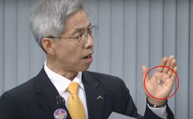 권영국 후보의 손바닥에 ‘民’(민)이라는 글자가 적혀 있다. [TV토론회 갈무리]