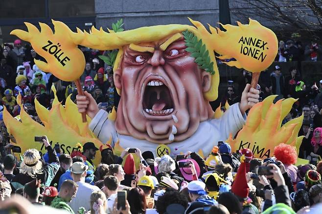 지난 3월3일 독일 뒤셀도르프에서 열린 전통적 로즈 카니발 퍼레이드에 불꽃에 둘러싸인 도널드 트럼프 미 대통령을 묘사한 카니발 수레 주변에 '병합, 관세, 기후 파괴, 대량 추방'이라는 문구가 쓰여 있다. /AP=뉴시스