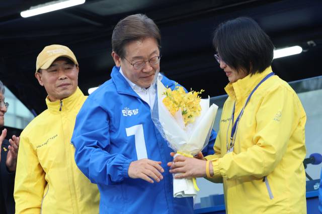 ▲더불어민주당 이재명 대선 후보가 24일 경기 안산시 단원구 안산문화광장에서 열린 유세에서 세월호 참사 유가족인 정부자씨로부터 프리지어 꽃을 받고 있다. ⓒ연합뉴스